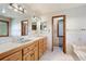 Bright bathroom with double vanity, neutral tiling, and access to bathtub at 1961 S Xenia Ct, Denver, CO 80231