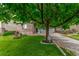 Charming home featuring a well-manicured lawn, mature tree, and a classic brick facade at 11716 Fairplay St, Commerce City, CO 80603
