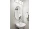 This bathroom boasts a pedestal sink, oval mirror, and a modern three-light vanity fixture at 5099 S Robb St, Littleton, CO 80127
