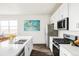 Bright kitchen with white cabinetry, stainless steel appliances, quartz countertops, and hardwood floors, creating an efficient space at 5099 S Robb St, Littleton, CO 80127
