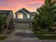Two-story home featuring stone accents, an attached two-car garage, and professionally landscaped yard during a colorful sunset at 5358 Ventura St, Denver, CO 80249