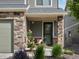 Charming front porch area with a stone-accented facade, a green front door, and beautiful landscaping at 5358 Ventura St, Denver, CO 80249
