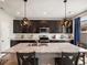 Modern kitchen island with a sink, dark cabinets, light countertops, and hanging pendant lights at 5358 Ventura St, Denver, CO 80249