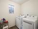 Well-lit laundry room with a modern washer and dryer, complemented by a decorative stained-glass window at 5358 Ventura St, Denver, CO 80249