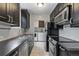 Galley kitchen featuring dark cabinets, stainless steel appliances, and an adjacent laundry area at 2640 S Marion St # 2646, Denver, CO 80210