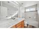 Well-lit bathroom featuring a tub-shower combo, storage cabinet, and modern sink at 16351 E 104Th Pl, Commerce City, CO 80022