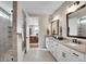 Elegant bathroom featuring double vanities, a glass shower, tile flooring, and access to the main bedroom at 8829 Animas River St, Littleton, CO 80125