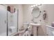 A well-lit bathroom featuring a glass-enclosed shower, pedestal sink, and modern fixtures at 14883 Roslyn Way, Thornton, CO 80602