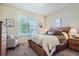 Comfortable bedroom has a wooden headboard, neutral decor, and a seating area by a sunny window at 14883 Roslyn Way, Thornton, CO 80602