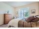 Comfortable bedroom has a wooden headboard, neutral decor, and a seating area by a sunny window at 14883 Roslyn Way, Thornton, CO 80602