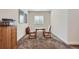 A compact dining area features a round table and chairs, complemented by neutral walls and ample natural light at 14883 Roslyn Way, Thornton, CO 80602