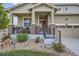 Inviting front porch with brick pillars, decorative railing, and landscaped garden with charming decorations at 14883 Roslyn Way, Thornton, CO 80602