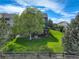 Aerial view of the backyard featuring a lush lawn, mature trees, a fire pit and a deck with stairs at 23427 Song Bird Hills Pl, Parker, CO 80138