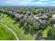 Aerial view of the neighborhood featuring the green home with a well-manicured lawn, set against a lush green landscape at 23427 Song Bird Hills Pl, Parker, CO 80138