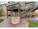 Spacious backyard patio with brick fire pit and outdoor seating underneath a wooden deck with stairs at 23427 Song Bird Hills Pl, Parker, CO 80138
