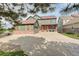 Charming two-story green home featuring a brick facade, covered porch, and spacious driveway at 23427 Song Bird Hills Pl, Parker, CO 80138
