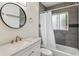 Modern bathroom with gray tiled walls, a shower and tub, and a round mirror above the sink at 2196 W 56Th Ave, Denver, CO 80221