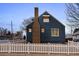 Charming blue home with white picket fence and brick chimney, showcasing classic curb appeal at 285 E Dartmouth Ave, Englewood, CO 80113