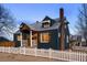 Charming blue home featuring a white picket fence, brick chimney, wood accents, and tasteful window awnings at 285 E Dartmouth Ave, Englewood, CO 80113