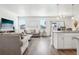 Bright living room with hardwood floors, a cozy seating area, and an open layout to the kitchen at 7414 E 158Th Pl, Thornton, CO 80602