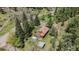 Aerial view of a charming cabin featuring a spacious deck surrounded by lush trees and a detached garage at 11080 S Deer Creek Rd, Littleton, CO 80127