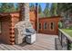 Outdoor stone fireplace and grill on wooden deck, perfect for outdoor cooking and entertaining at 11080 S Deer Creek Rd, Littleton, CO 80127