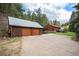 Exterior shot showing a two-car garage beside a rustic cabin in a wooded setting at 11080 S Deer Creek Rd, Littleton, CO 80127