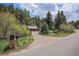 Charming property entrance with a mailbox, wooden fence, and driveway leading to a home in the woods at 11080 S Deer Creek Rd, Littleton, CO 80127