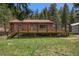 Cozy cabin featuring a spacious deck, metal roof, and natural surroundings on a green lawn at 11080 S Deer Creek Rd, Littleton, CO 80127