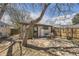 Backyard view with stone patio and wooden privacy fence with home behind tree at 3064 S Cherokee St, Englewood, CO 80110