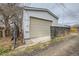 A detached one car garage features a tan sectional garage door and a white painted exterior at 3064 S Cherokee St, Englewood, CO 80110