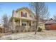 A tan two-story home with a covered porch, red window shutters, and a well-maintained lawn on a sunny day at 1157 Mircos St, Erie, CO 80516