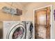 Functional laundry room with a washer, dryer, storage shelves, and a stylish wooden door at 1157 Mircos St, Erie, CO 80516