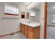 Bathroom with two windows, sink, mirror, and wood cabinets at 9693 W Euclid Dr, Littleton, CO 80123