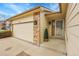 Inviting front entrance with tan siding and a two-car garage featuring stone accents at 9693 W Euclid Dr, Littleton, CO 80123