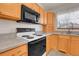 Well-lit kitchen featuring oak cabinets, white appliances, and gray countertop at 9693 W Euclid Dr, Littleton, CO 80123