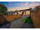 Backyard of brick home with a walkway, lawn, and a wood fence under a colorful sunset at 3329 N High St, Denver, CO 80205