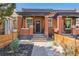 Charming red brick home featuring a cozy front porch and beautifully landscaped front yard with a modern fence at 3329 N High St, Denver, CO 80205