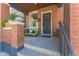 Inviting front porch features a charming green bench, brick pillars, and a well-maintained entryway at 3329 N High St, Denver, CO 80205