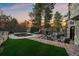 Landscaped backyard with a patio, pool, outdoor fireplace, and lush trees at 5085 Knobcone Dr, Castle Rock, CO 80108