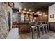 Home bar with seating, dark wood paneling, and stone accents at 5085 Knobcone Dr, Castle Rock, CO 80108