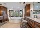 Bright bathroom featuring a luxurious soaking tub, wood cabinets, and ample natural light at 5085 Knobcone Dr, Castle Rock, CO 80108