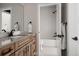 Well-lit bathroom with a wood vanity, white countertops, tile backsplash and a tub/shower combo at 27608 E Ottawa Ave, Aurora, CO 80016