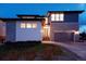 Home featuring a two-car garage, stone and siding accents, and a modern front door at night at 27608 E Ottawa Ave, Aurora, CO 80016