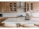 Close-up view of a kitchen showcasing wood cabinets, patterned backsplash, stainless steel hood, and a white countertop island at 27608 E Ottawa Ave, Aurora, CO 80016