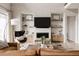 Living room with built-in shelves, a fireplace, a large window, a brown sectional sofa, and a modern accent chair at 27608 E Ottawa Ave, Aurora, CO 80016