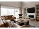 Bright living room featuring a brown sectional sofa, a large window, a modern accent chair, and a decorative fireplace at 27608 E Ottawa Ave, Aurora, CO 80016