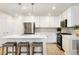 Bright, modern kitchen features stainless appliances, white cabinets, light countertops, and an island with stool seating at 320 Marshall Mews, Superior, CO 80027