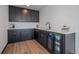 Modern bar area with sleek cabinetry, quartz countertop, beverage refrigerator, and hardwood floors at 6047 N Nepal Ct, Aurora, CO 80019