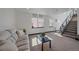Bright living room featuring a sofa, large windows, and open staircase at 6047 N Nepal Ct, Aurora, CO 80019
